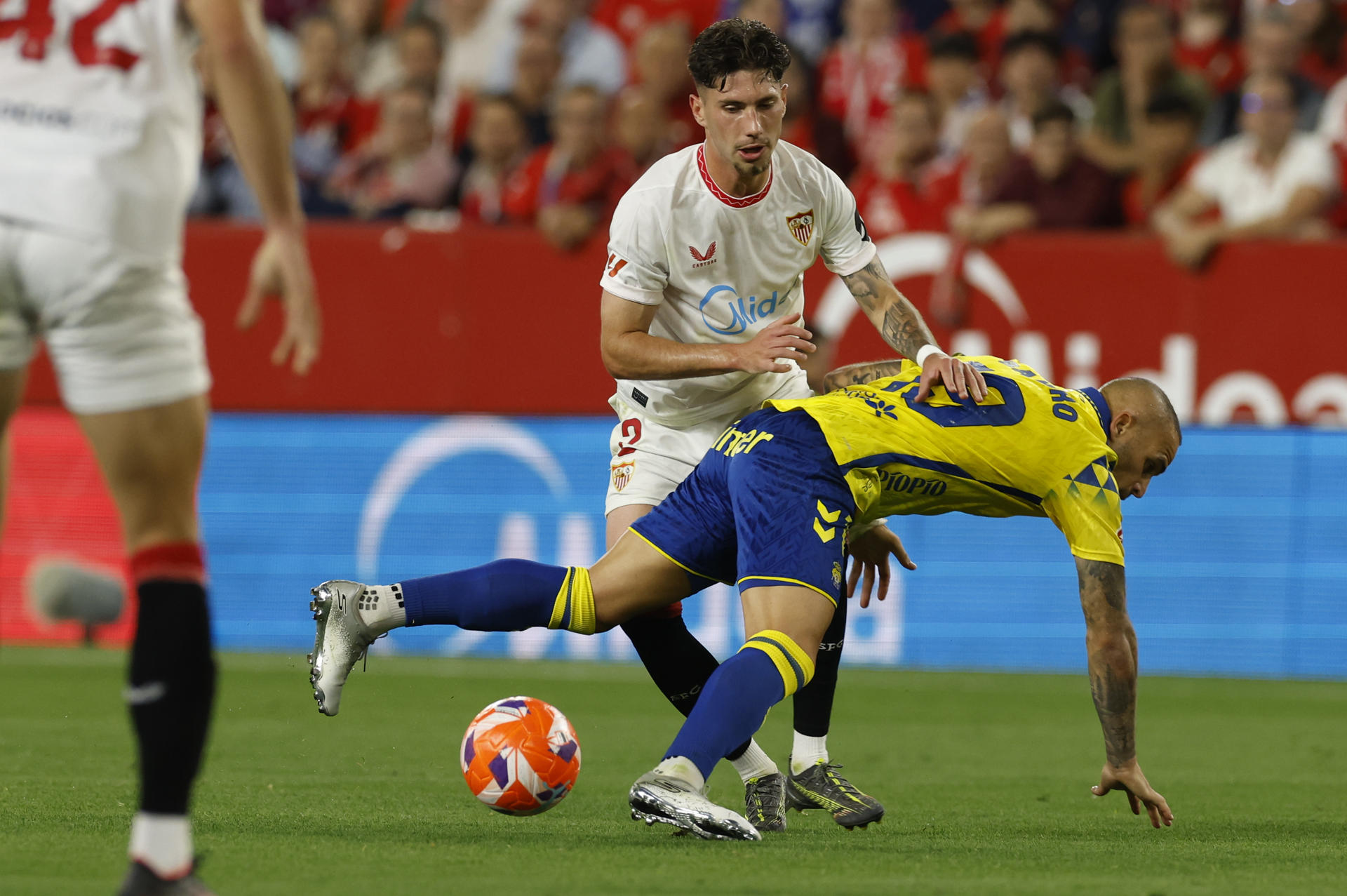 El delantero de Las Palmas Sandro Ramírez (d) cae ante José Ángel Carmona, del Sevilla, durante el partido de LaLiga de fútbol que Sevilla FC y UD Las Palmas disputan en el estadio Ramón Sánchez-Pizjuán. EFE/Julio Muñoz