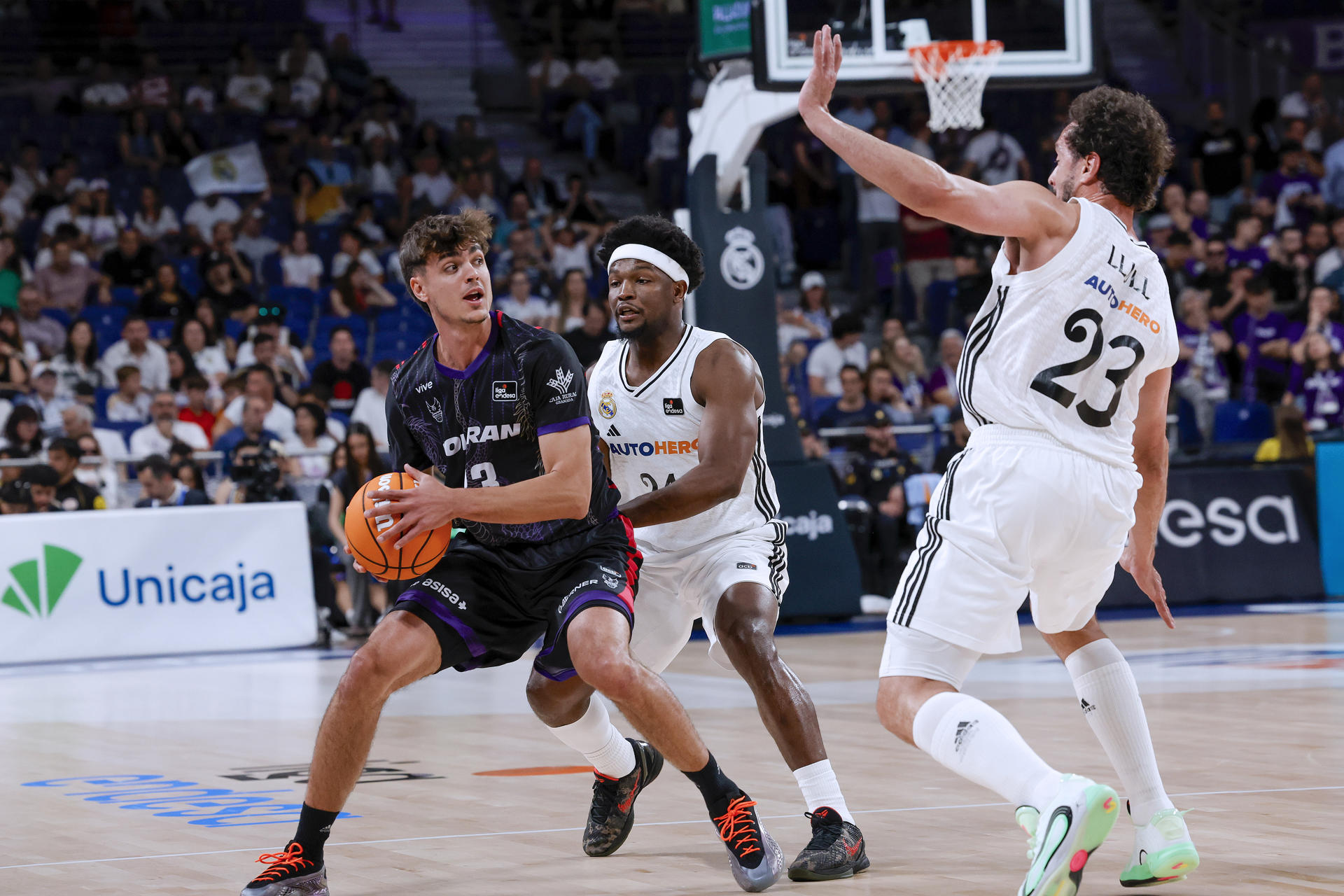 El base dominicano del Real Madrid Andres Feliz (c) en acción ante el base italiano del Granada Riccardo Visconti (i) este domingo, en el partido de la Liga Endesa de baloncesto, entre el Real Madrid y el Granada, en la capital española. EFE/ Zipi