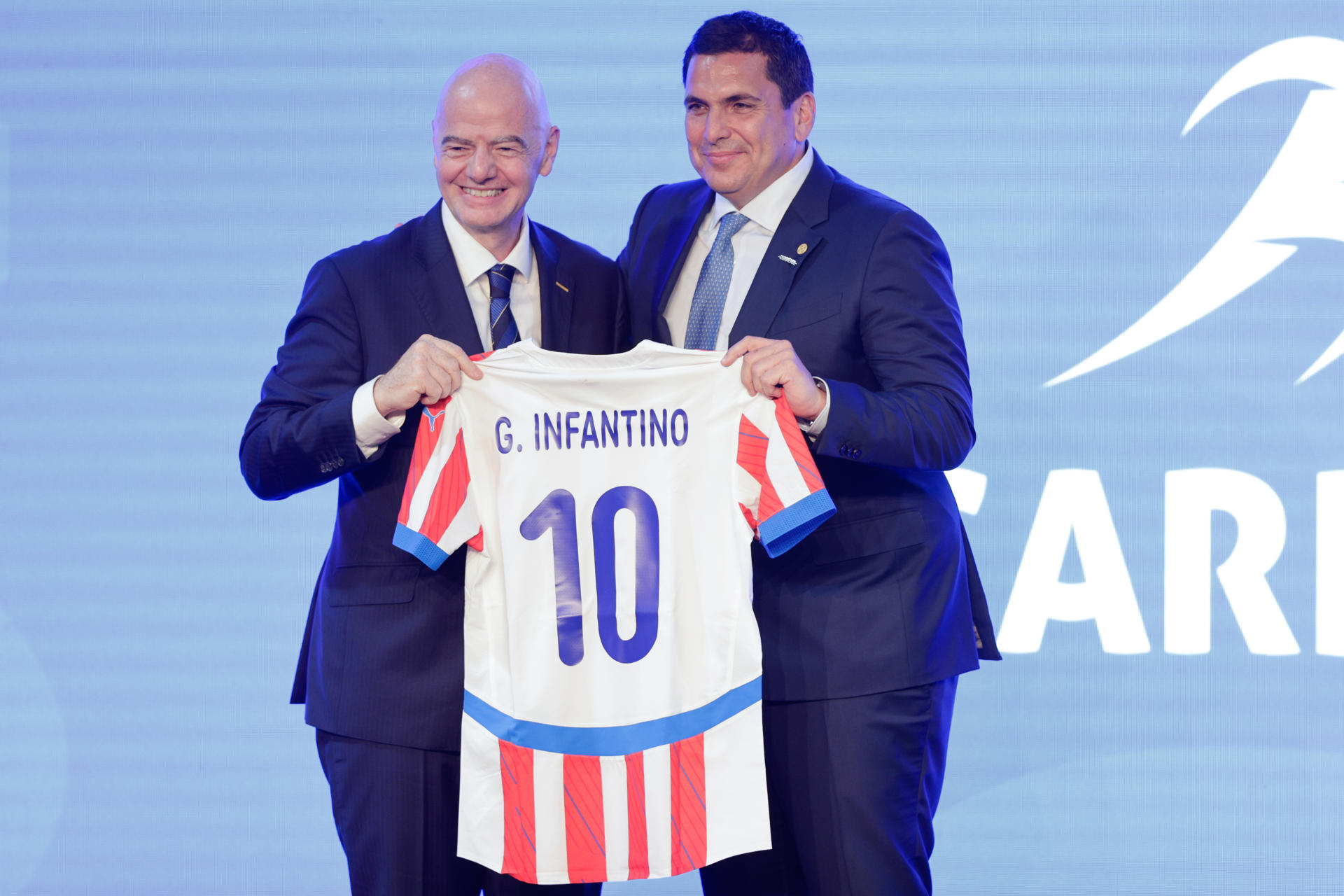 El presidente de la FIFA, Gianni Infantino (i), posa con una camiseta de Paraguay obsequiada por el presidente de la Asociación Paraguaya de Fútbol, Robert Harrison, en el acto de inauguración del pabellón social del Centro de Rendimiento para Divisiones Formativas de la Asociación Paraguaya de Fútbol, en Luque (Paraguay). EFE/ Juan Pablo Pino