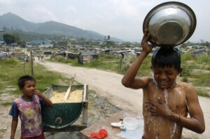 Fotografía de archivo de un niño al bañarse al aire libre, en la comunidad Las Victorias, en Soyapango (El Salvador). EFE/Roberto Escobar