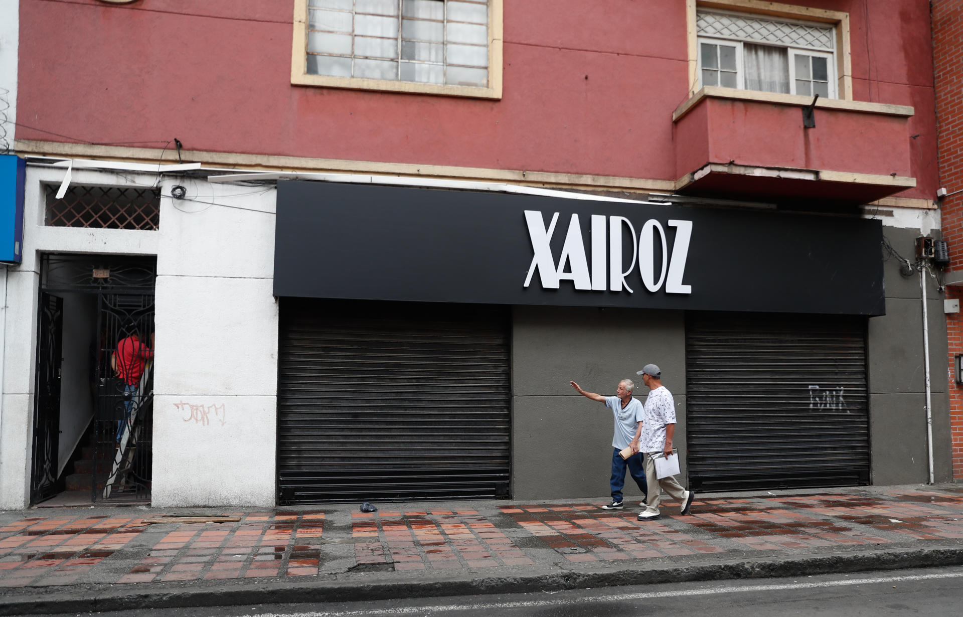 Personas caminan frente a locales comerciales cerrados este miércoles, en el centro de Cali (Colombia). EFE/Ernesto Guzmán