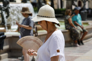 Una mujer se protege del sol y calor con sombrero y abanico den Valencia. EFE/Ana Escobar