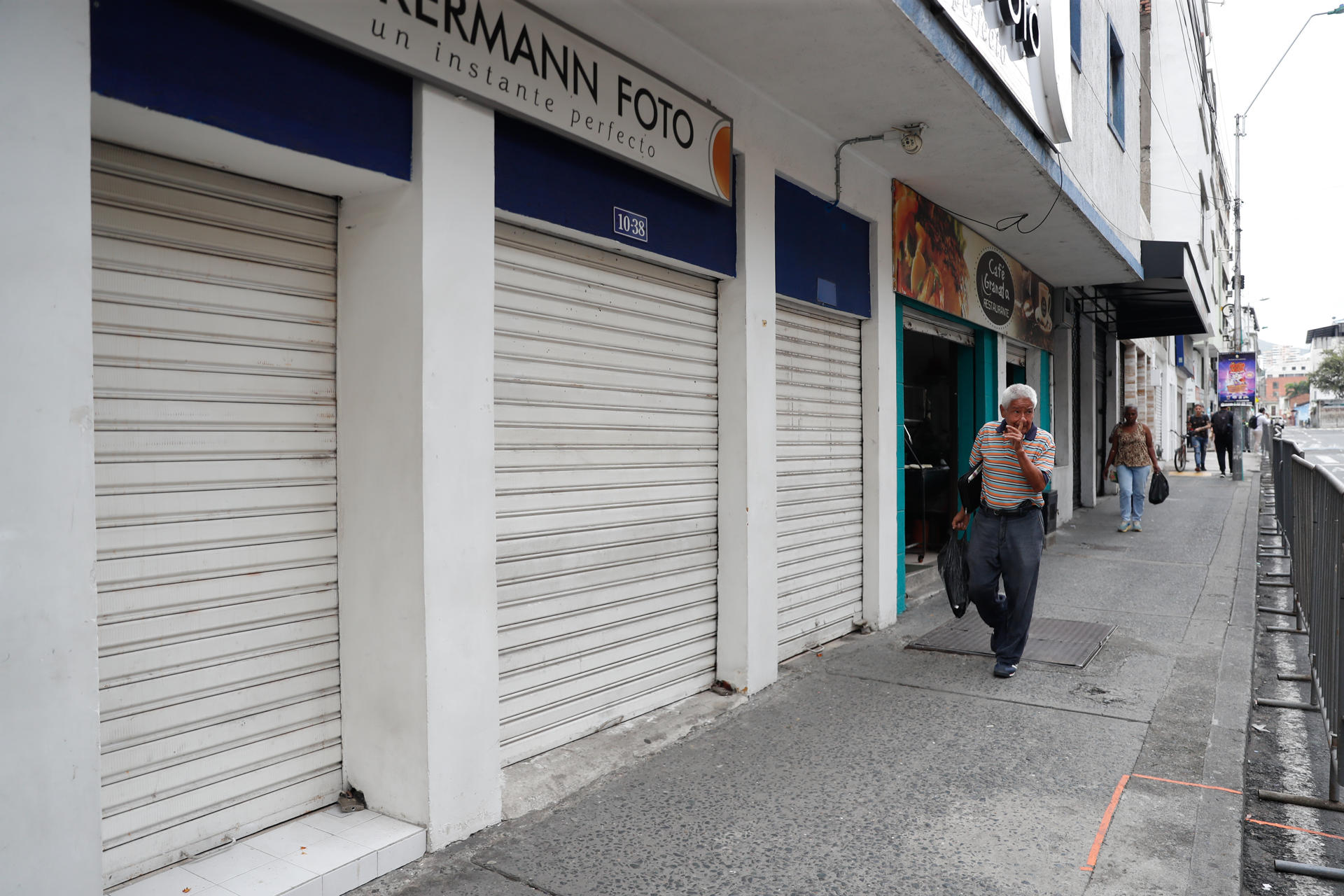 Personas caminan frente a locales comerciales cerrados este miércoles, en el centro de Cali (Colombia). EFE/Ernesto Guzmán