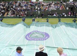 Imagen de archivo en la que oficiales de pista cubren con una lona la pista central de Wimbledon. EFE/Andy Rain