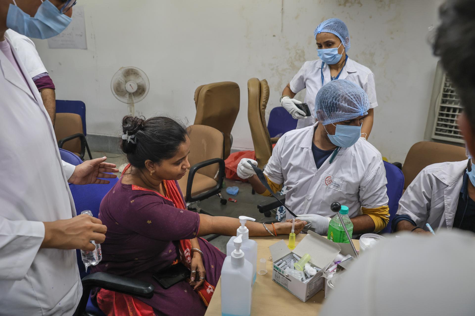 Los médicos recogen una muestra de ADN de un familiar de una víctima que murió en el accidente aéreo del vuelo AI-171 de Air India, en el Hospital Civil de Ahmedabad, Gujarat, oeste de la India, el 13 de junio de 2025. EFE/EPA/RAJAT GUPTA