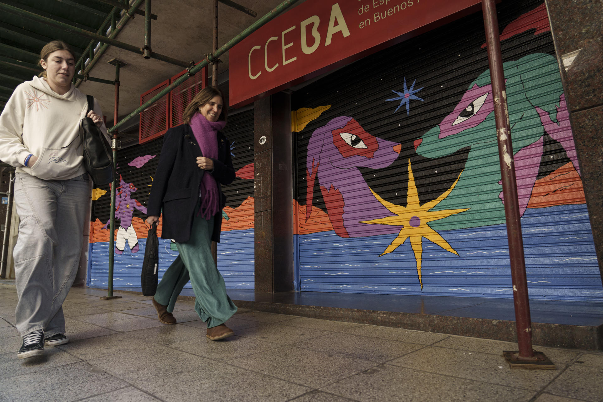 Fotografía tomada el pasado 26 de junio de un par de mujeres al caminar frente a un mural alegórico con motivo del vigésimo aniversario del matrimonio igualitario en España y el décimo quinto en Argentina, en el Centro Cultural de España, en Buenos Aires (Argentina). EFE/Pablo Barrera