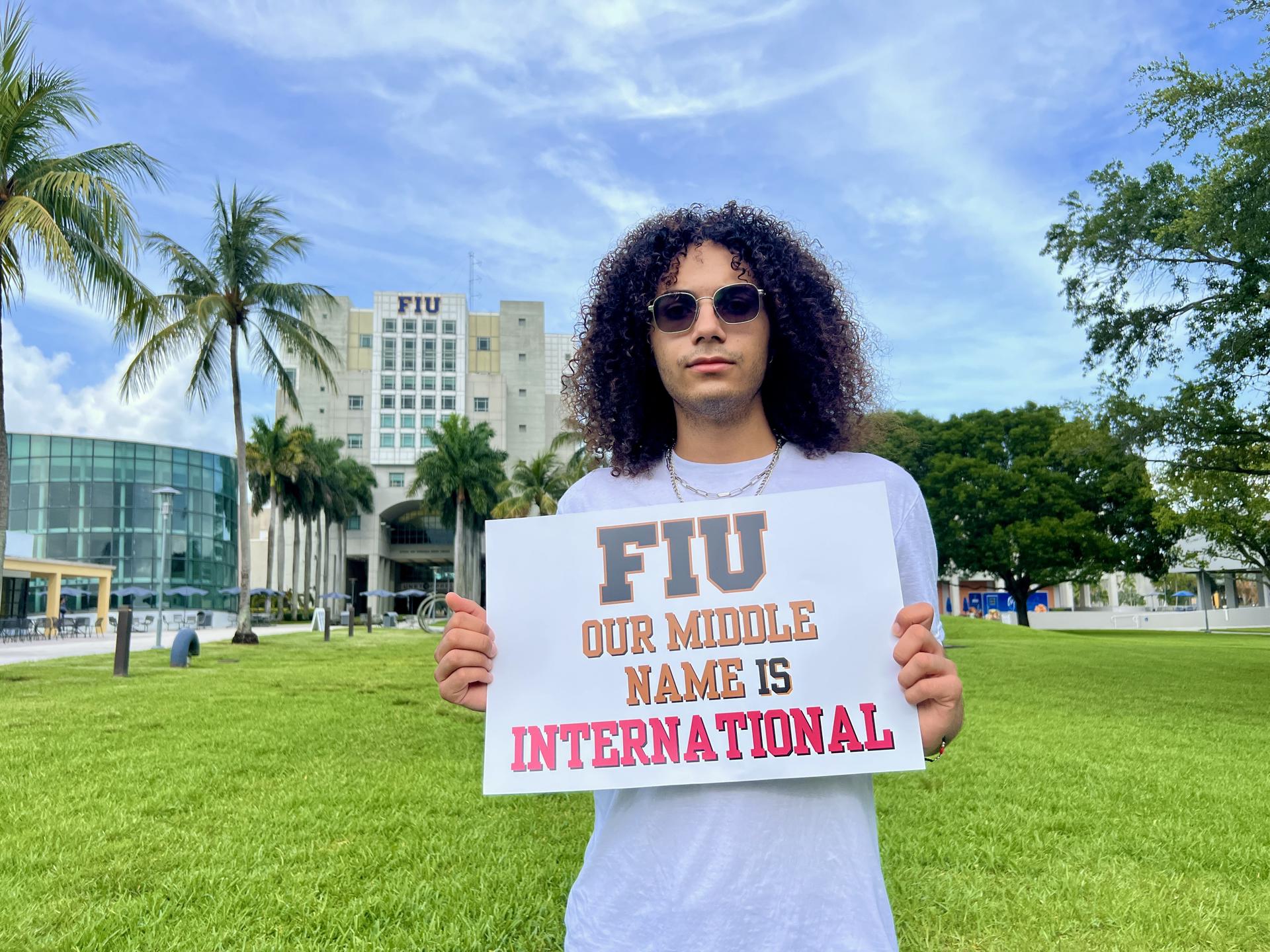 Dariel Gómez, estudiante de sociología de la Universidad Internacional de Florida (FIU), posa con un cartel durante una protesta en el campus de la institución académica este jueves, en Miami (Estados Unidos). EFE/Alberto Boal