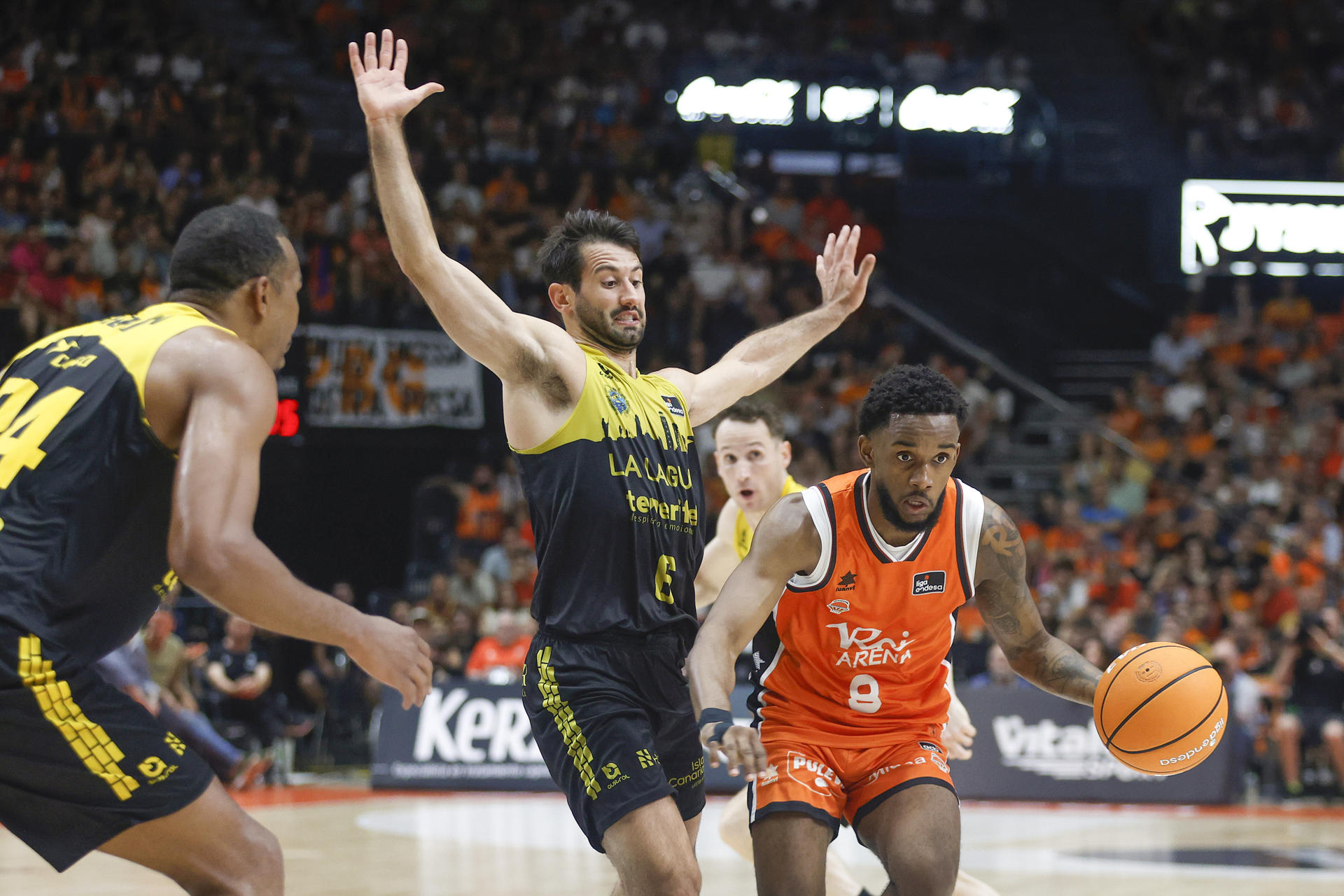 El escolta del Valencia Jean Montero (d) juega un balón ante Bruno Fitipaldo (c), del Tenerife, durante el segundo partido de la semifinal de la Liga Endesa de baloncesto que Valencia Basket y La Laguna Tenerife disputan este jueves en el pabellón de la Fuente de San Luis. EFE/Miguel Ángel Polo