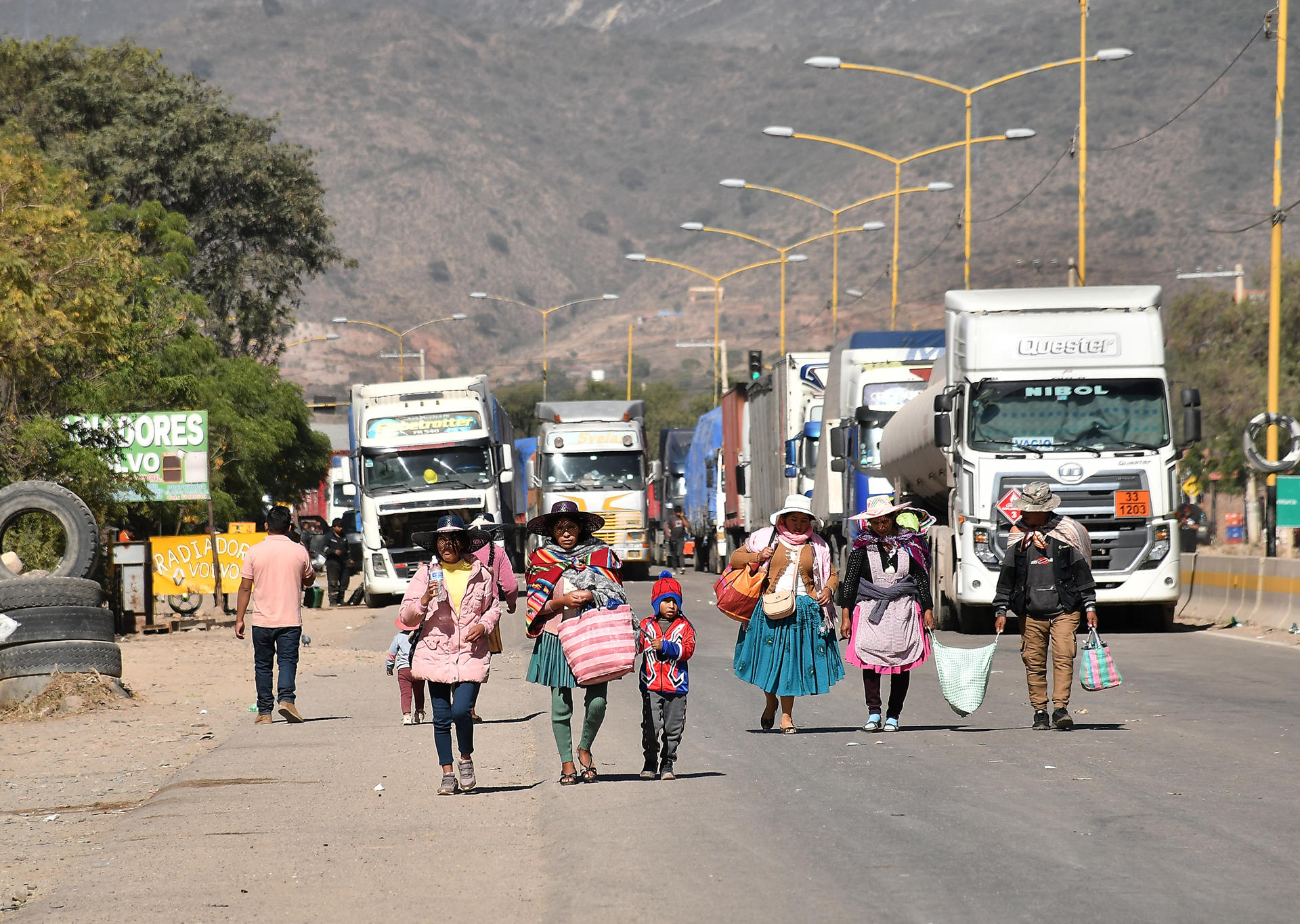 Personas caminan por una carretera tras un bloqueo realizado por seguidores del exmandatario Evo Morales este lunes, en Sipe Sipe en la región de Cochabamba (Bolivia). EFE/ Jorge Abrego