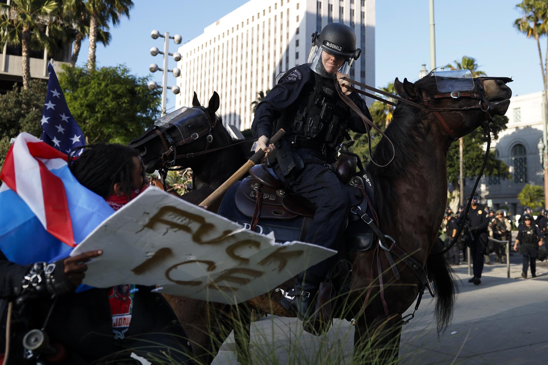 Oficiales del Departamento de Policía de Los Ángeles se enfrentan este miércoles con manifestantes frente al Ayuntamiento de Los Ángeles (EE.UU.). EFE/EPA/CAROLINE BREHMAN