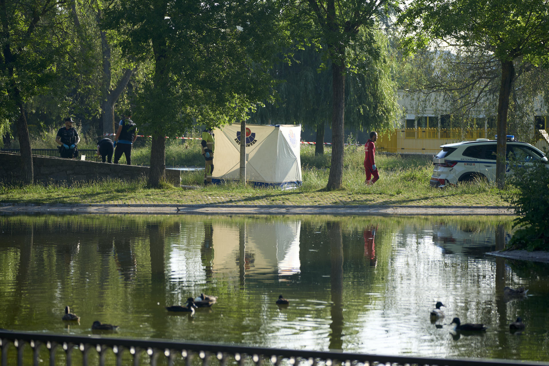 Miembros de la Ertzaintza trabajan en el lugar donde un hombre fue hallado alrededor de las siete de la mañana de este martes flotando en un estanque del parque de San Martín de Vitoria. EFE/ L. Rico