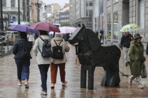 Viandantes con paraguas bajo la lluvia en Oviedo. EFE/Paco Paredes