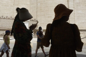 Turistas se tapan con sombreros mientras caminan por el centro histórico de Sevilla, este martes en el que cinco comunidades de la península se encuentran en nivel de riesgo naranja (importante), con temperaturas de hasta 41 grados en Andalucía.EFE/José Manuel Vidal