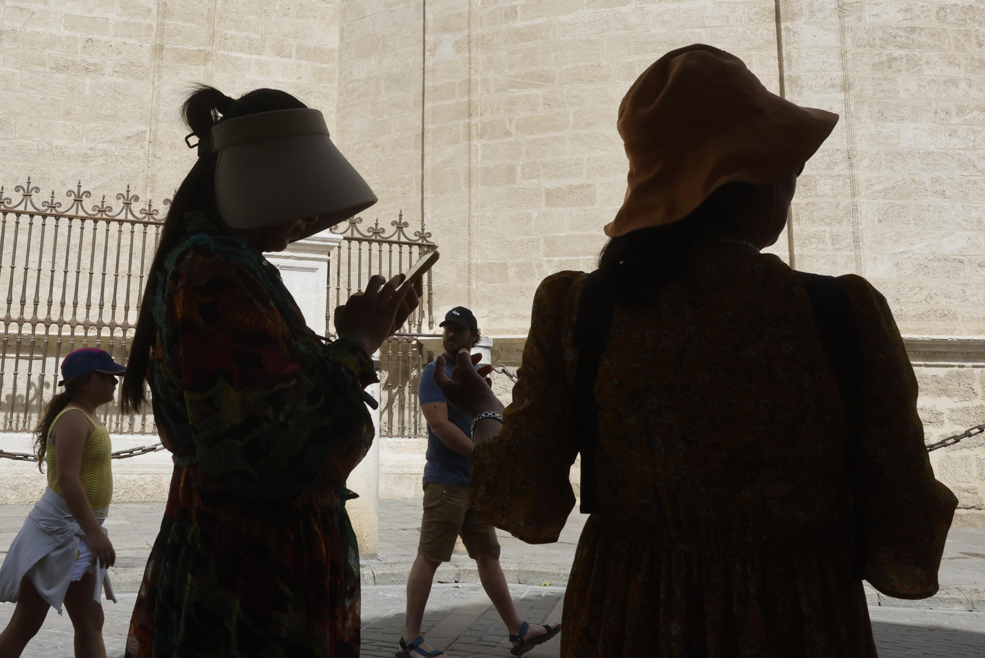 Turistas se tapan con sombreros mientras caminan por el centro histórico de Sevilla, este martes en el que cinco comunidades de la península se encuentran en nivel de riesgo naranja (importante), con temperaturas de hasta 41 grados en Andalucía.EFE/José Manuel Vidal
