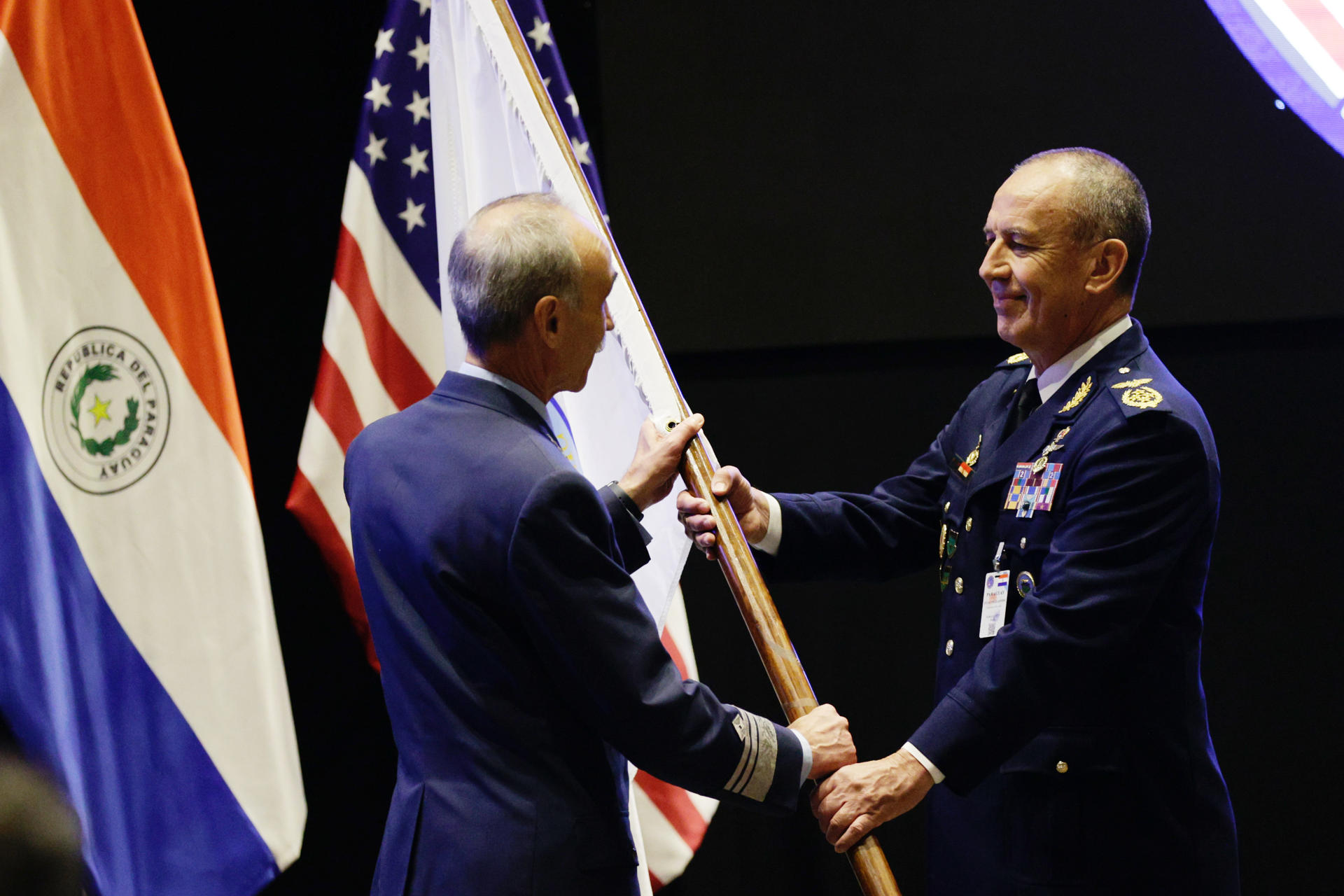 El jefe de la Fuerza Aérea Argentina, Gustavo Valverde (i), entrega la bandera de la conferencia al comandante de la Fuerza Aérea Paraguaya, Julio Fullaondo (d), durante la LXV Conferencia de Jefes de las Fuerzas Aéreas Americanas (Conjefamer 2025), del Sistema de Cooperación entre las Fuerzas Aéreas Americanas (Sicofaa) este martes en Luque (Paraguay). EFE/ Juan Pablo Pino
