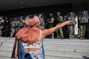 Un mujer fue capada este martes, 10 de junio, al increpar a miembros de la Guardia Nacional de California que custodian la entrada del edificio federal, durante las protestas contra su presencia y las redadas a migrantes presuntamente indocumentados, en Los Ángeles (CA, EE.UU.). EFE/Allison Dinner