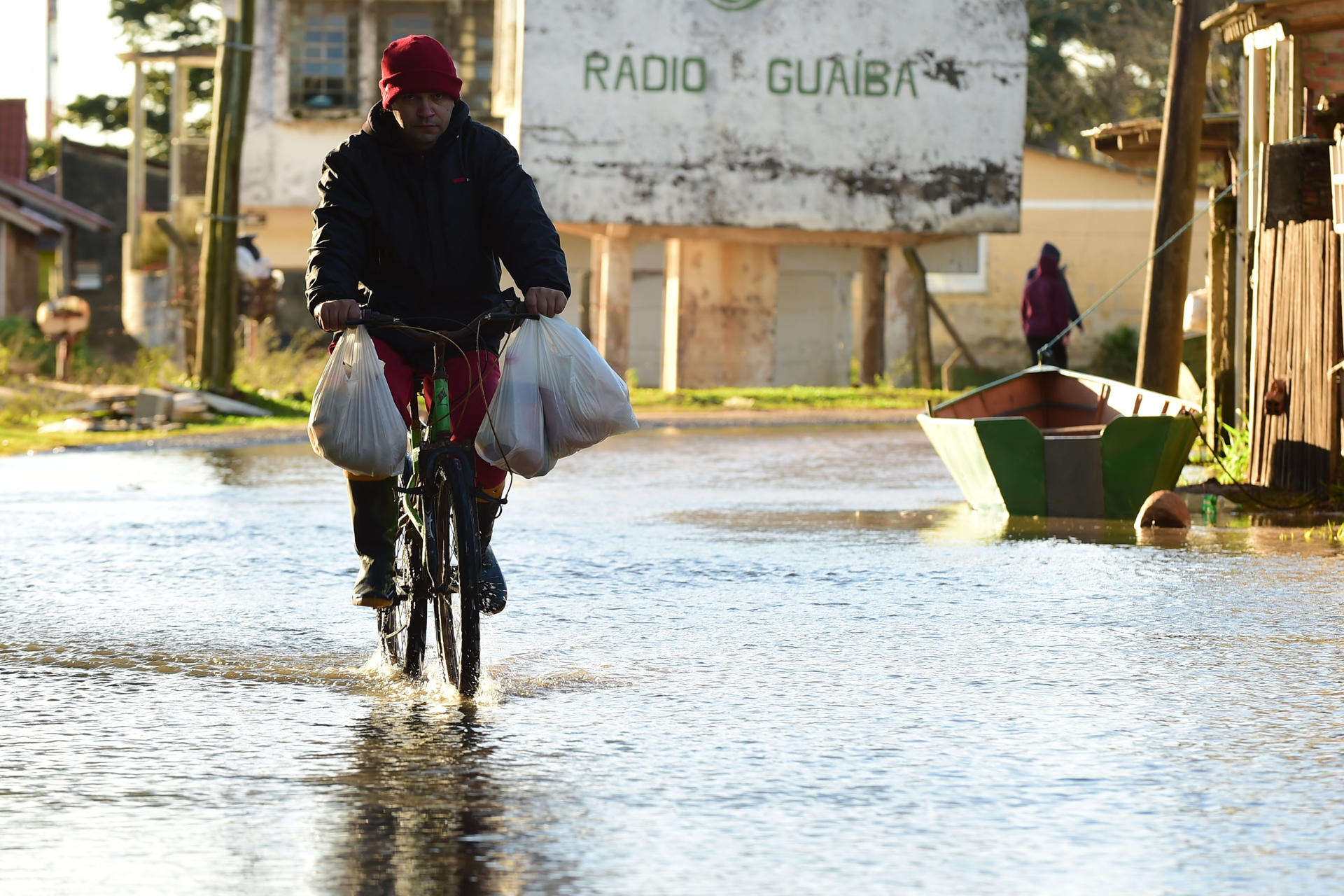 Un hombre pasa en bicicleta por una calle inundada tras el desbordamiento del río Guaíban que inundó una sección de la costa este lunes, en Porto alegre (Brasil). EFE/ Ricardo Rimoli