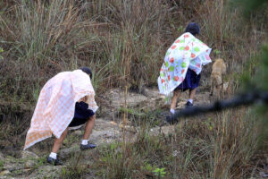Fotografía de archivo de un par de niñas, protegidas con plásticos por la lluvia, de camino a una escuela rural, cerca de Tegucigalpa (Honduras). EFE/Gustavo Amador