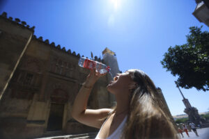 Una mujer se refresca con agua mientras camina junto a la Mezquita Catedral de Córdoba, este viernes en el que ya se nota un ascenso térmico en casi toda España y en el que por la tarde se superarán los 40 grados en Andalucía a las puertas de la primera ola de calor del verano.EFE /Salas