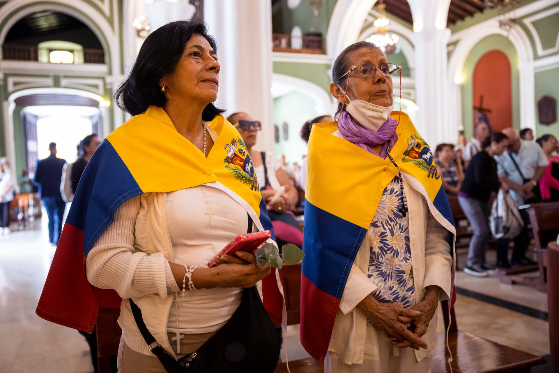 Fieles asisten a una eucaristía portando la bandera venezolana en la iglesia La Candelaria este viernes, en Caracas (Venezuela). EFE/ Miguel Gutiérrez