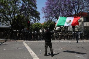 Un manifestante fue captado este sábado, 7 de junio, al sostener una bandera mexicana durante un enfrentamiento con agentes federales después de que el Servicio de Inmigración y Control de Aduanas (ICE) realizara una redada contra presuntos inmigrantes indocumentados, en Paramount (California, EE.UU.). EFE/Allison Dinner