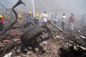 Unas personas apagan el fuego junto a los escombros en el lugar donde se estrelló este jueves un avión de Air India cerca del aeropuerto internacional de Ahmedabad, Gujarat (India). EFE/EPA/ Siddharaj Solanki
