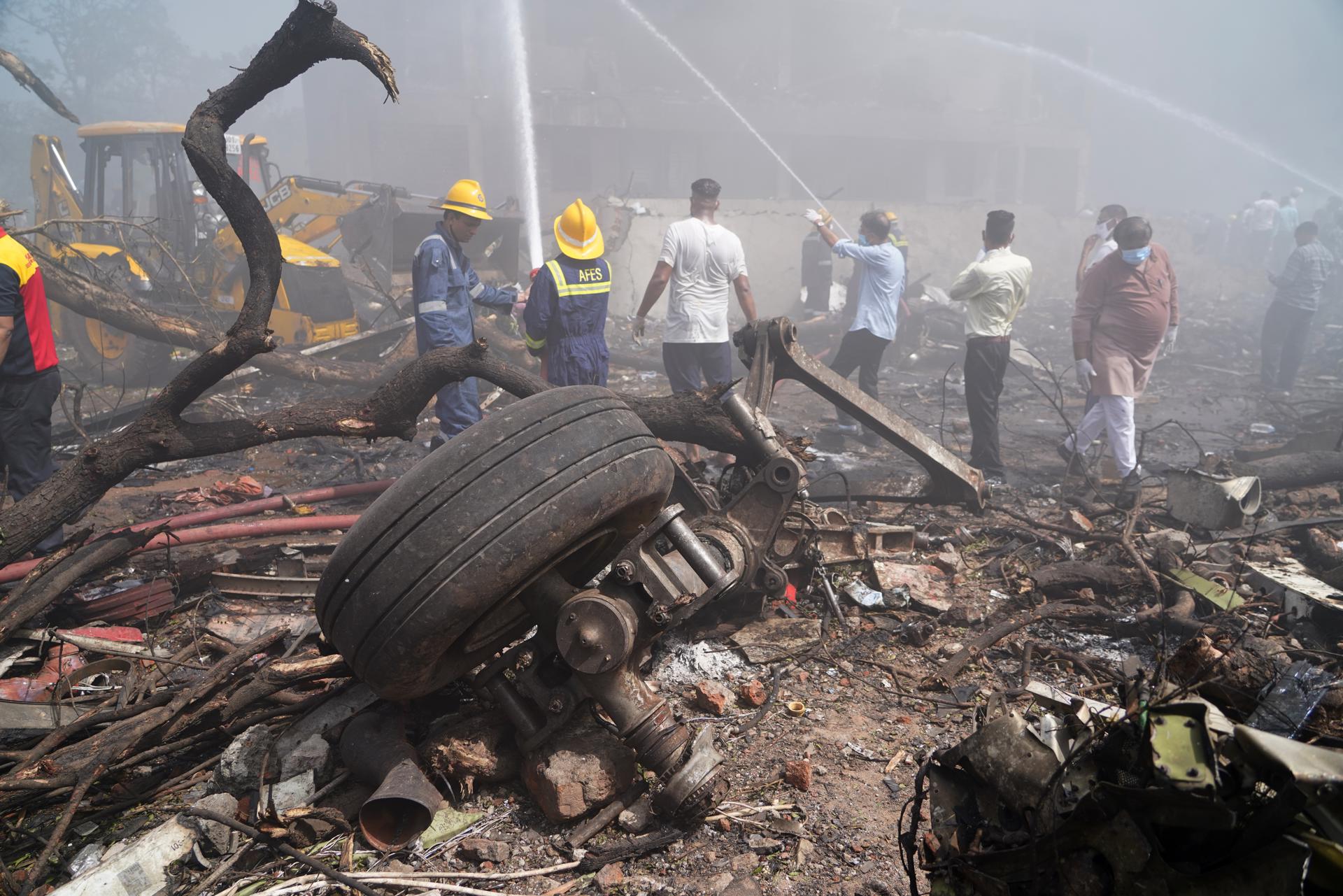 Unas personas apagan el fuego junto a los escombros en el lugar donde se estrelló este jueves un avión de Air India cerca del aeropuerto internacional de Ahmedabad, Gujarat (India). EFE/EPA/ Siddharaj Solanki