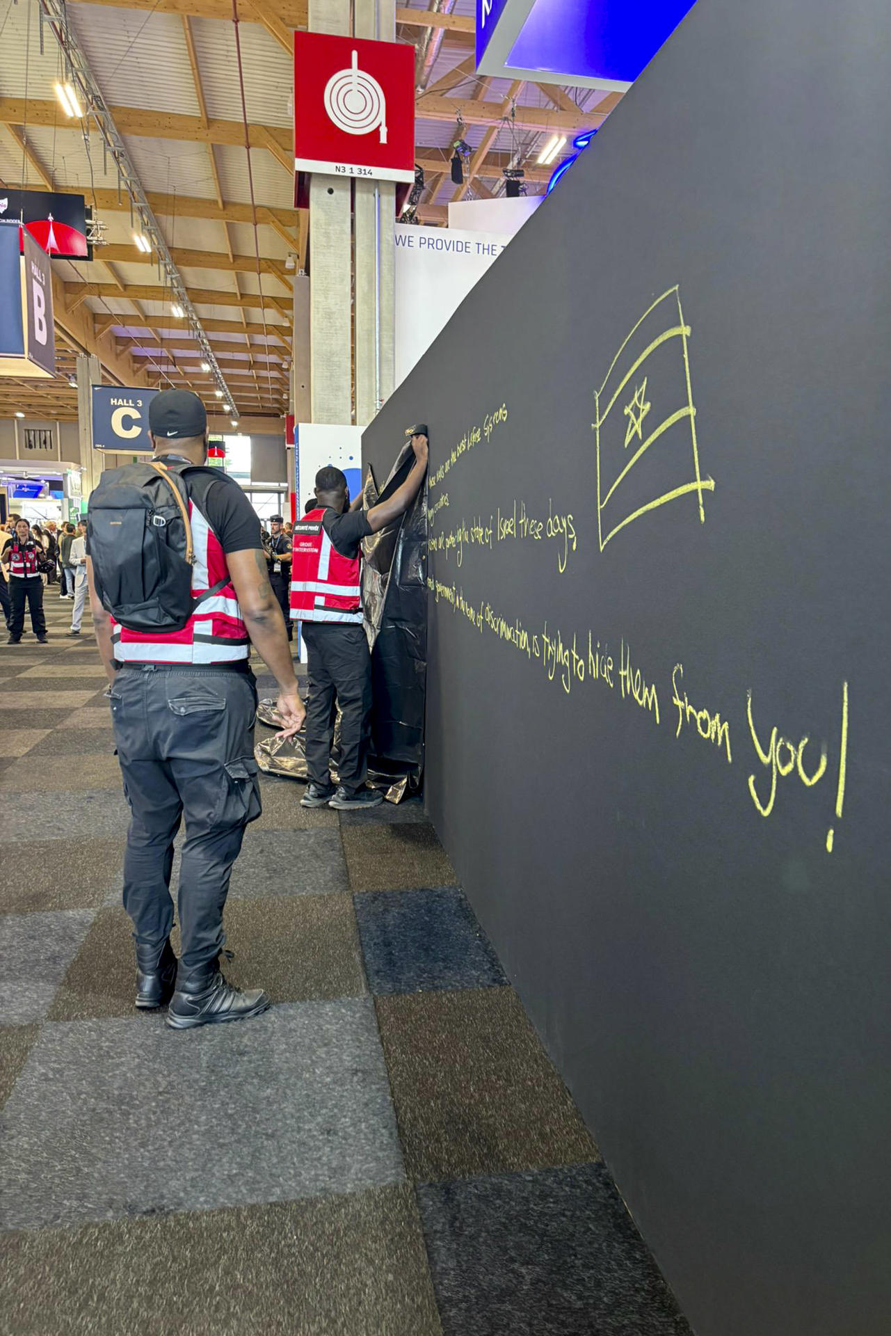 Personal del Salón Internacional de Aeronáutica y del Espacio de Le Bourget, la mayor feria del sector, cubre con una lona un mensaje político a favor de Israel escrito por una trabajadora en el stand de la empresa israelí Rafael, especializada en tecnología de defensa. EFE/ Rafael SOLO USO EDITORIAL/SOLO DISPONIBLE PARA ILUSTRAR LA NOTICIA QUE ACOMPAÑA (CRÉDITO OBLIGATORIO)