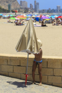 Una persona aguarda bajo una sombrilla en la playa de Alicante durante este jueves. EFE/Morell