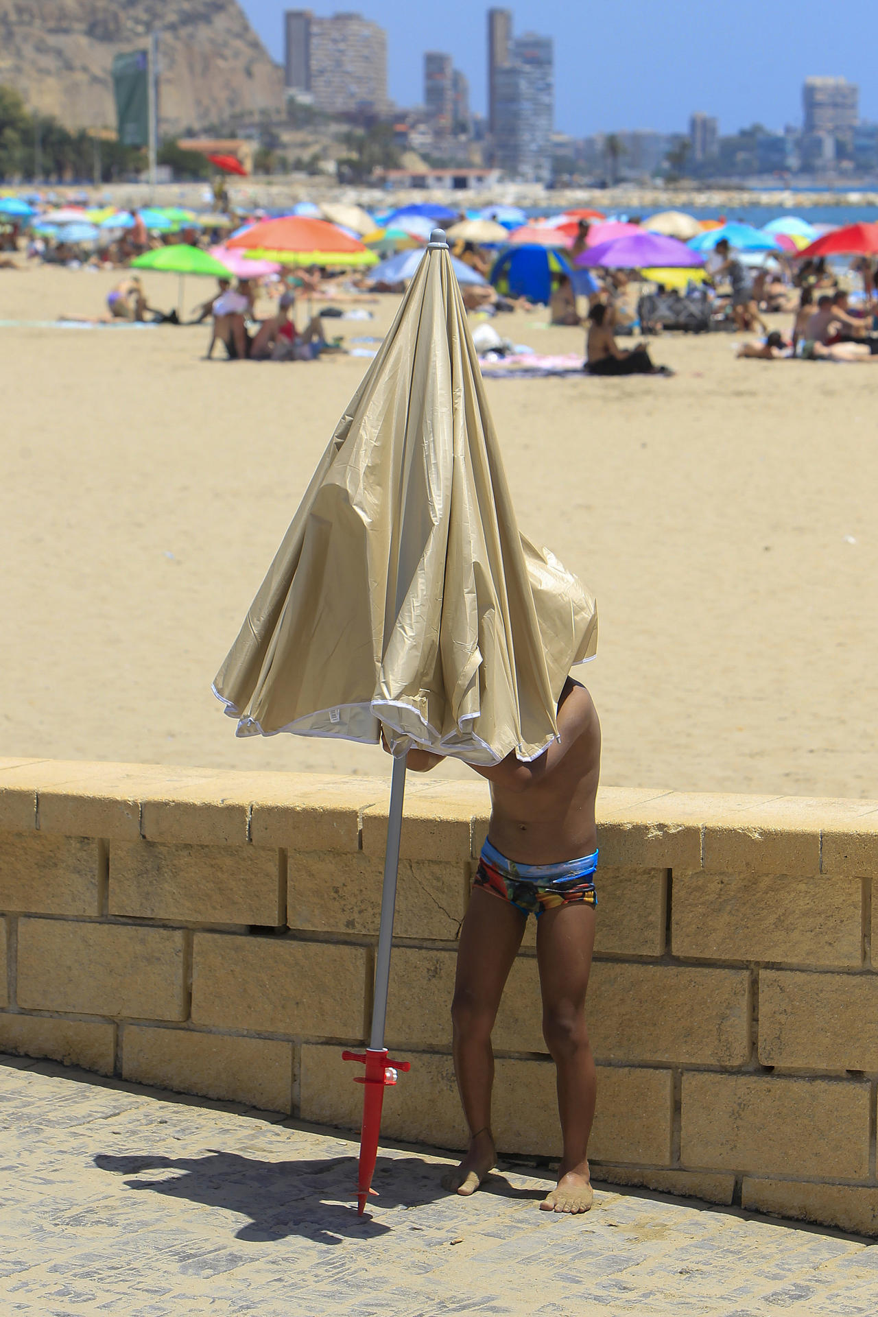 Una persona aguarda bajo una sombrilla en la playa de Alicante durante este jueves. EFE/Morell