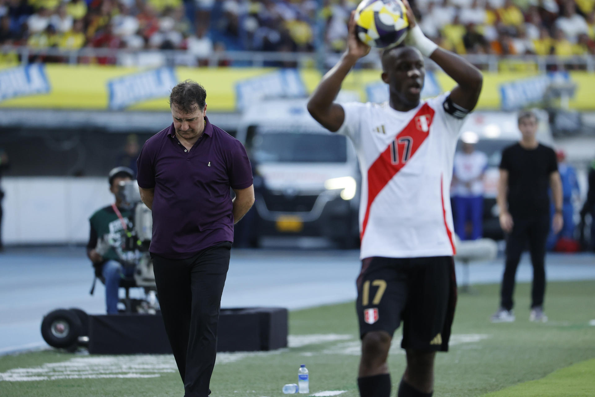 El peruano Luis Advincula cobra un saque de banda mientras los seleccionadores de Colombia, Néstor Lorenzo (i) y Perú, Óscar Ibáñez (d), observan. EFE/Mauricio Dueñas Castañeda