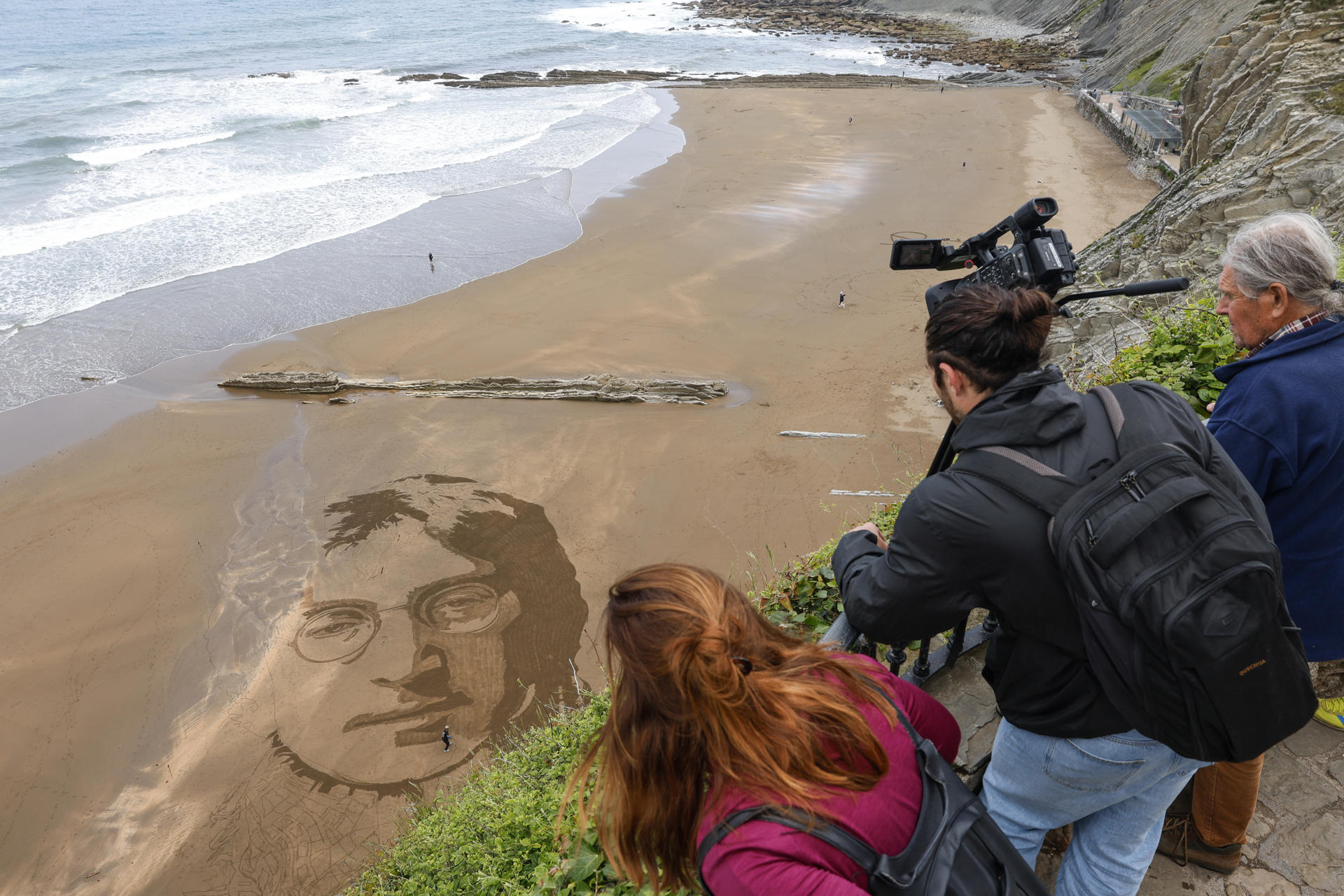 El arte efímero del peruano Germán Cedano se borra con la marea. Sus monumentales dibujos sobre la arena transforman la playa de La Concha de San Sebastián en un lienzo en el que este artista callejero graba retratos, mandalas y mensajes que se viralizan en redes y que, pese a su repercusión, nunca repite. En la imagen trabaja en un retrato del músico John Lennon creado en la playa de Itzurun de Zumaia (Gipuzkoa). EFE/Juan Herrero.