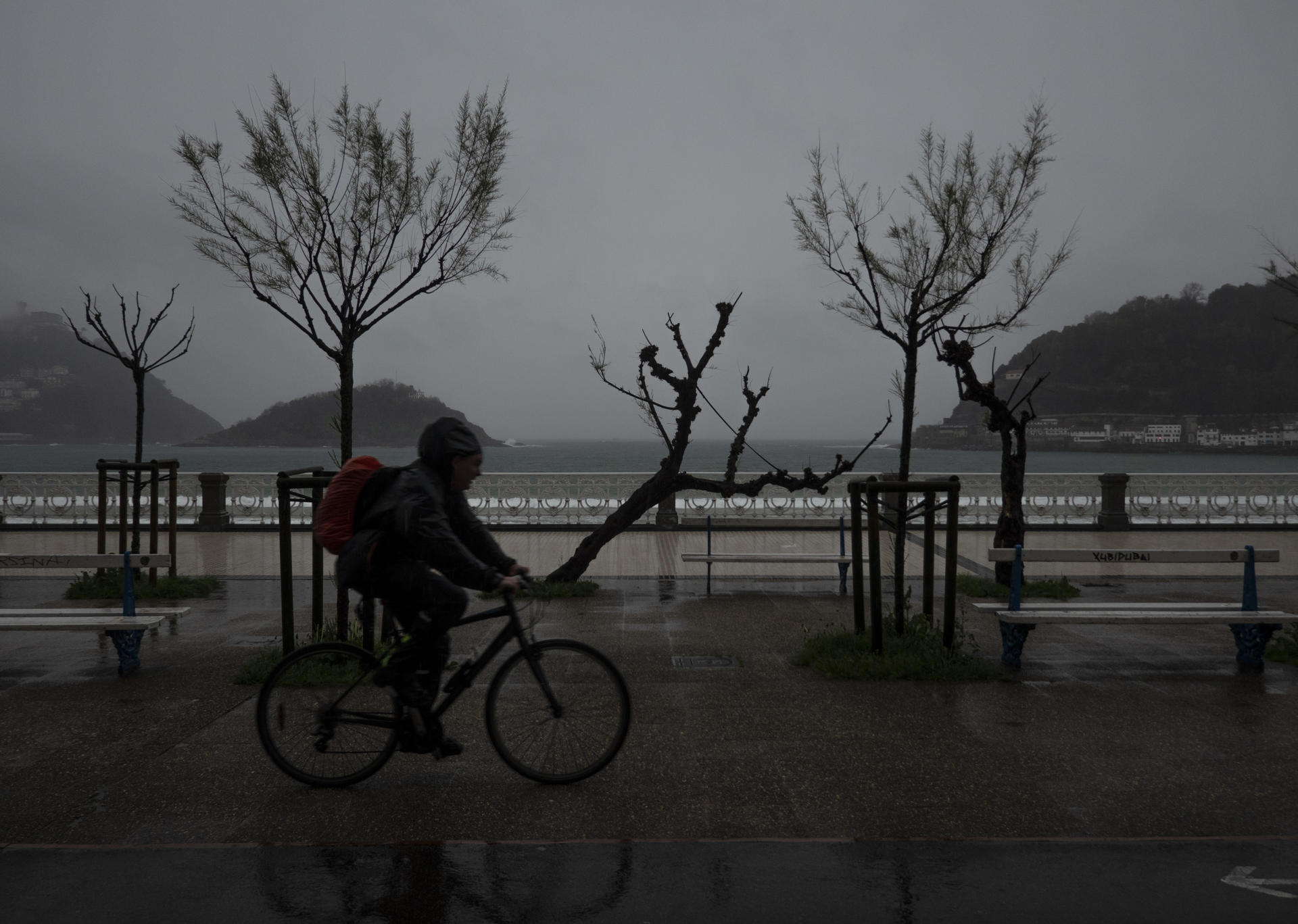 Un ciclista circula por el paseo de la Concha de San Sebastián bajo una intensa lluvia. EFE/Juan Herrero.