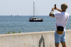 Un hombre saca una foto junto a un velero en la playa de la Malvarrosa en Valencia este lunes. EFE/ Ana Escobar