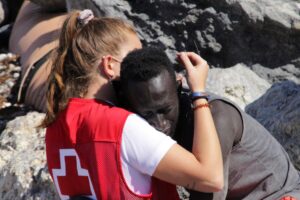 Imagen de archivo del joven migrante senegalés Abdou Ngomue abrazado a una voluntaria de la Cruz Roja nada más cruzar en mayo de 2021 uno de los espigones de Ceuta, una de las dos únicas fronteras terrestres de Europa con África. EFE/Reduan