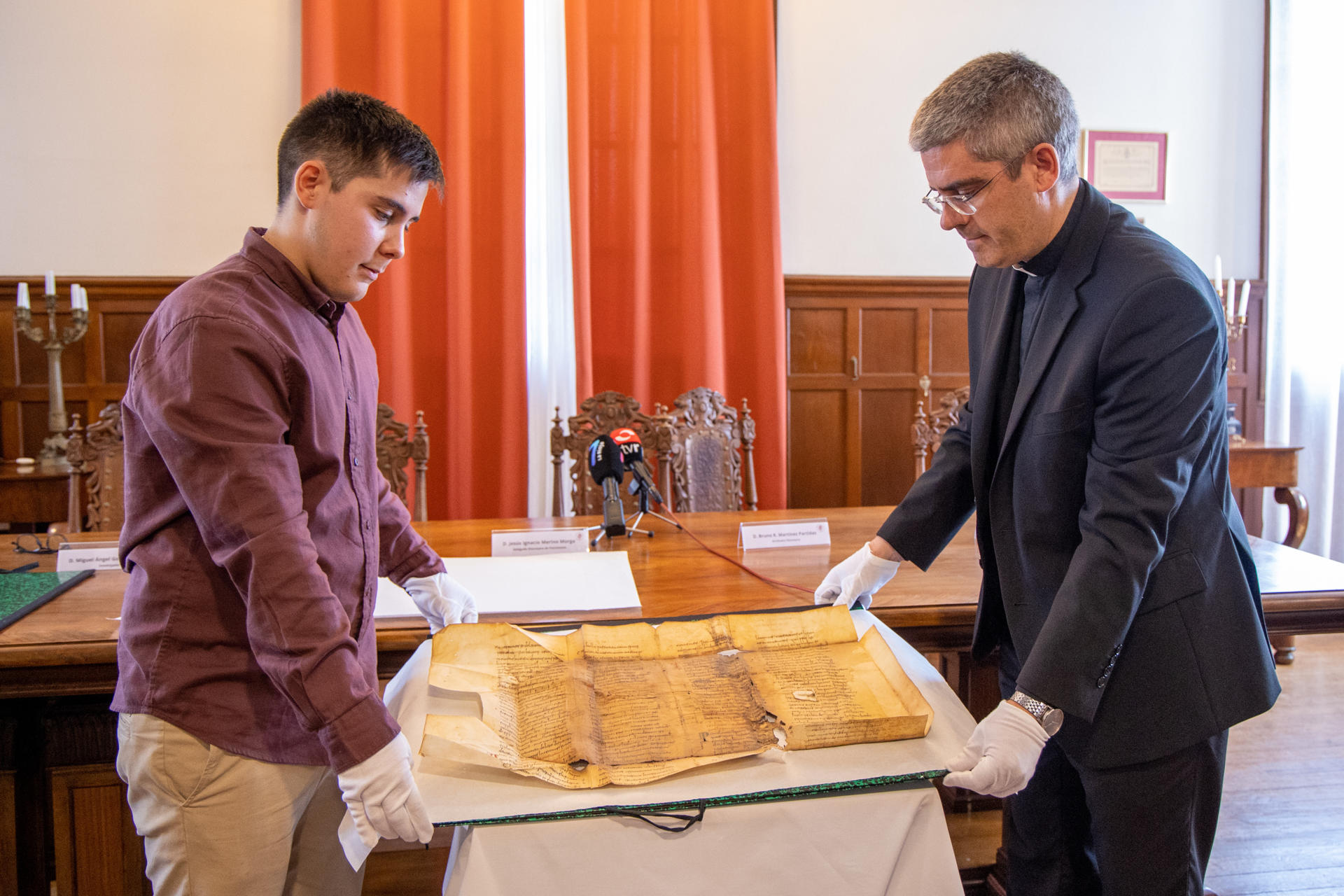 - El delegado episcopal de Patrimonio de la Diócesis riojana, Jesús Merino (d), y el archivero diocesano Bruno Martínez muestran este jueves durante rueda informativa un documento del siglo X "de gran valor histórico". EFE/ Raquel Manzanares