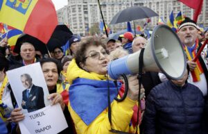 Fotografía del 26 de marzo de 2025 que muestra a una mujer que sostiene un retrato de Calin Georgescu mientras otra mujer grita consignas antigubernamentales durante una protesta contra la cancelación de la primera vuelta de las elecciones presidenciales en Rumanía. EFE/EPA/ROBERT GHEMENT