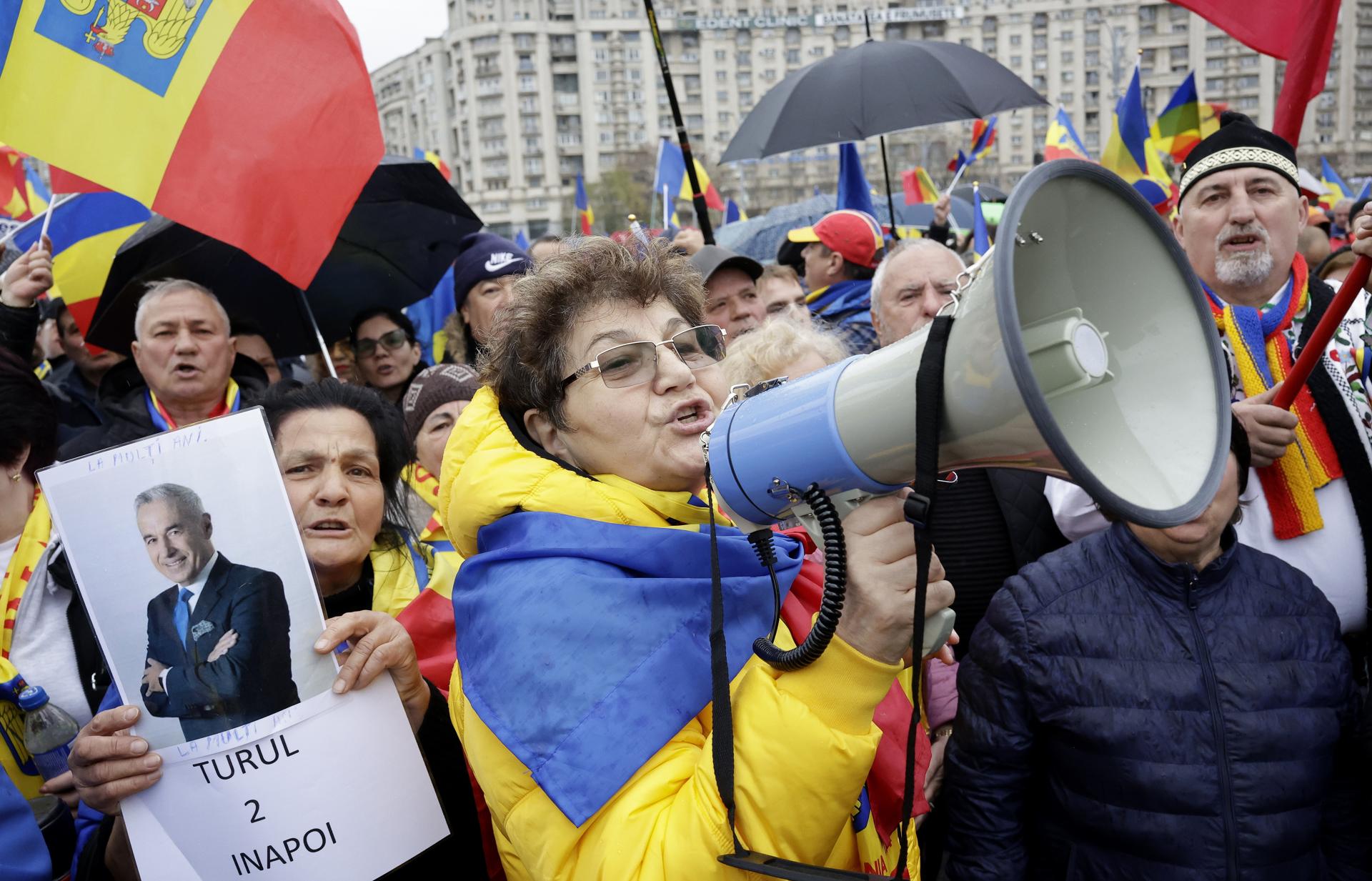 Fotografía del 26 de marzo de 2025 que muestra a una mujer que sostiene un retrato de Calin Georgescu mientras otra mujer grita consignas antigubernamentales durante una protesta contra la cancelación de la primera vuelta de las elecciones presidenciales en Rumanía. EFE/EPA/ROBERT GHEMENT
