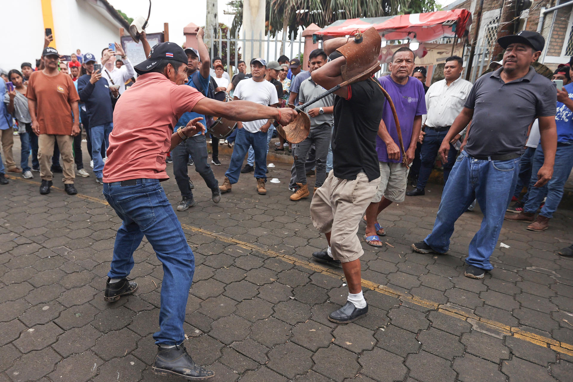 Personas se dan latigazos durante el tradicional baile de 'Los Chinegros' en honor a San Juan Bautista este martes, en San Juan de Oriente (Nicaragua). EFE/ STR