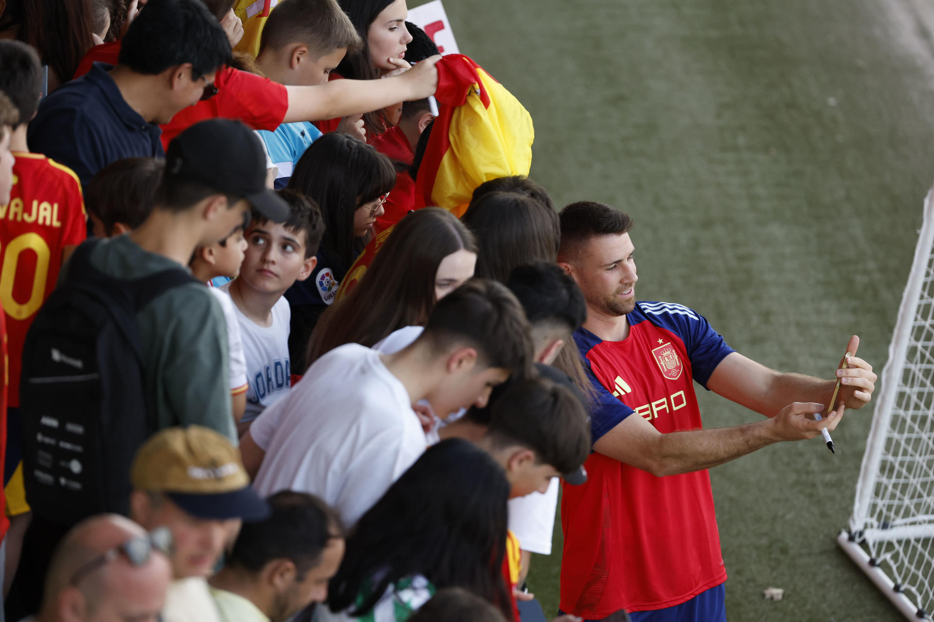 El portero de la selección española Unai Simón (d) posa con aficionados durante un entrenamiento del equipo en Las Rozas, Madrid. EFE/Juan Carlos Hidalgo