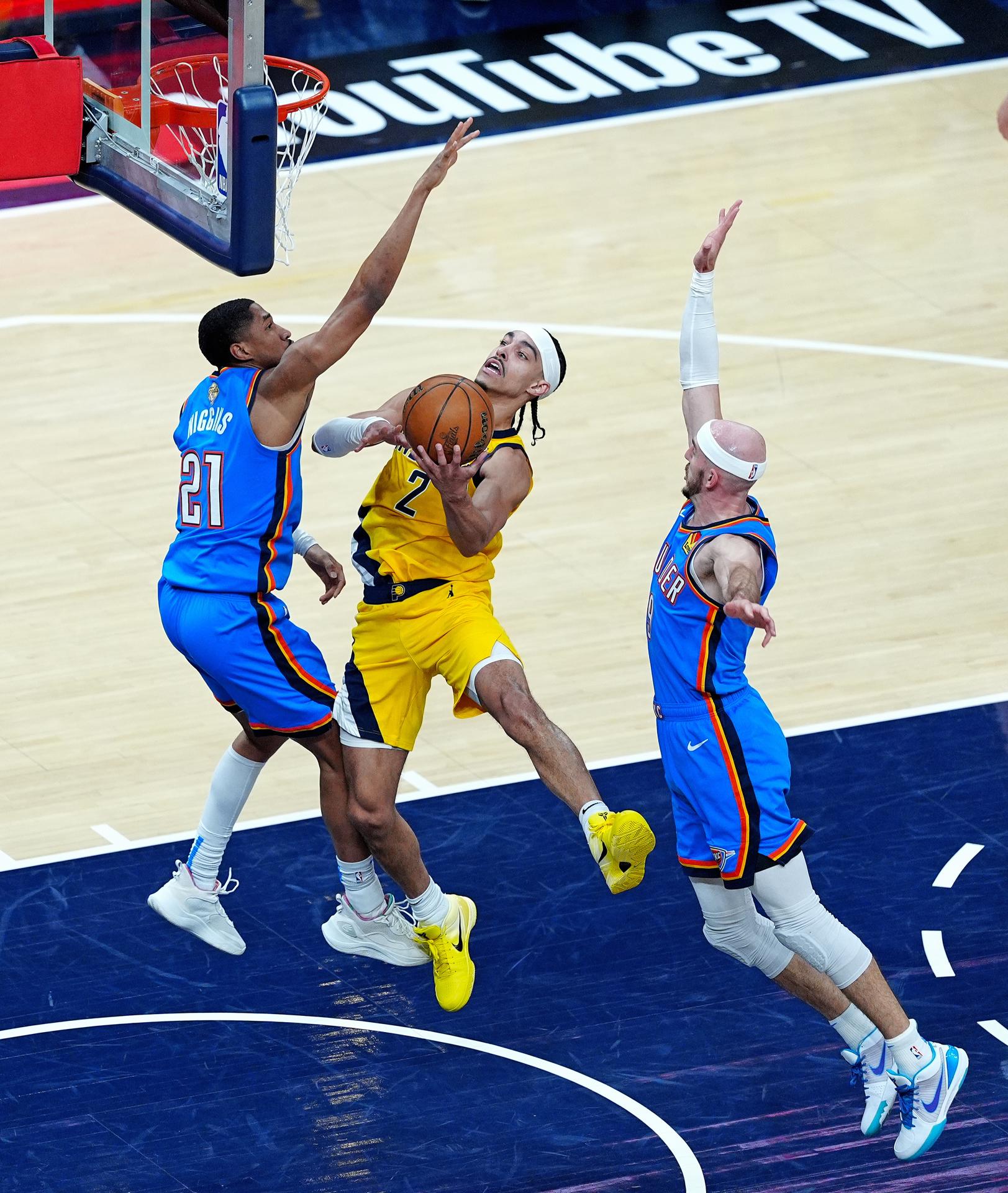 Andrew Nembhard (c) de los Indiana Pacers lanza con la marca de Aaron Wiggins (i) y Alex Caruso (d) de los Oklahoma City Thunder. EFE/Brian Spurlock