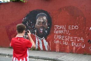 Un joven fotografía el mural dedicado a los hermanos Williams y otros jugadores del equipo rojiblanco en la localidad vizcaína de Barakaldo que ha sufrido un acto vandálico, en el que se ha borrado con pintura la cara de Nico. EFE/ Luis Tejido