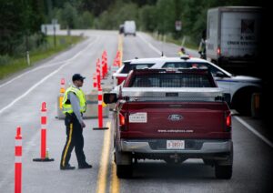 Un oficial de la Real Policía Montada de Canadá (RCMP) interroga al conductor de un vehículo en un puesto de control en Kananaskis, Alberta, Canadá, el 15 de junio de 2025. EFE/EPA/Spencer Colby