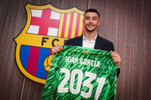 El portero Joan García posa junto al escudo tras firmar el contrato con el FC Barcelona hasta 2031 en un acto privado en las oficinas de su nuevo club. EFE/FC Barcelona/German Parga ***SÓLO USO EDITORIAL/SOLO USO PERMITIDO PARA ILUSTRAR LA NOTICIA QUE APARECE EN EL PIE DE FOTO*** (CRÉDITO OBLIGATORIO)