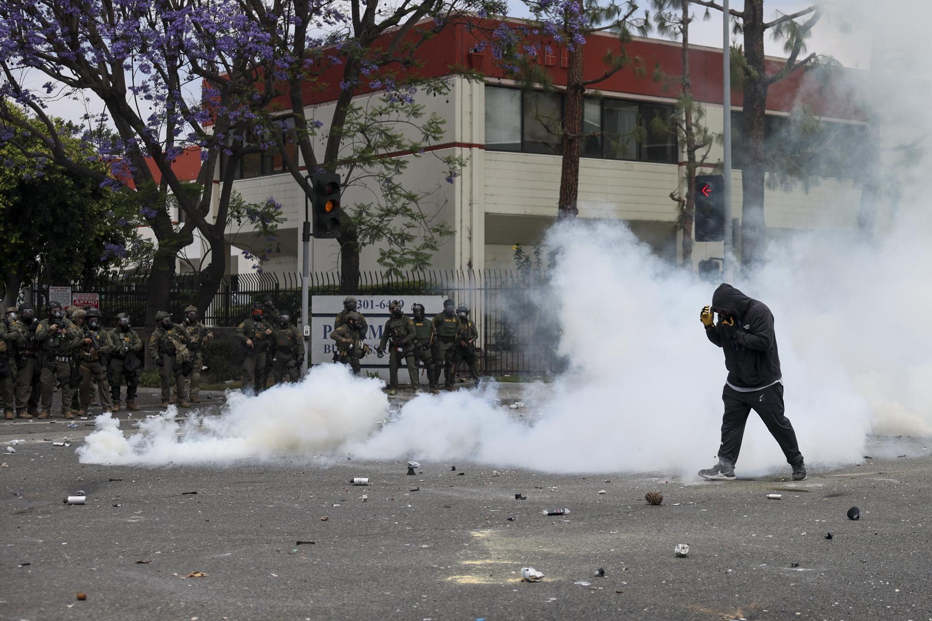 Un manifestante camina a través del humo de granadas de humo aturdidoras disparadas por agentes federales cerca de un Home Depot después de que el Servicio de Inmigración y Control de Aduanas (ICE) realizara una redada en Paramount, California, EE.UU. EFE/ALLISON DINNER