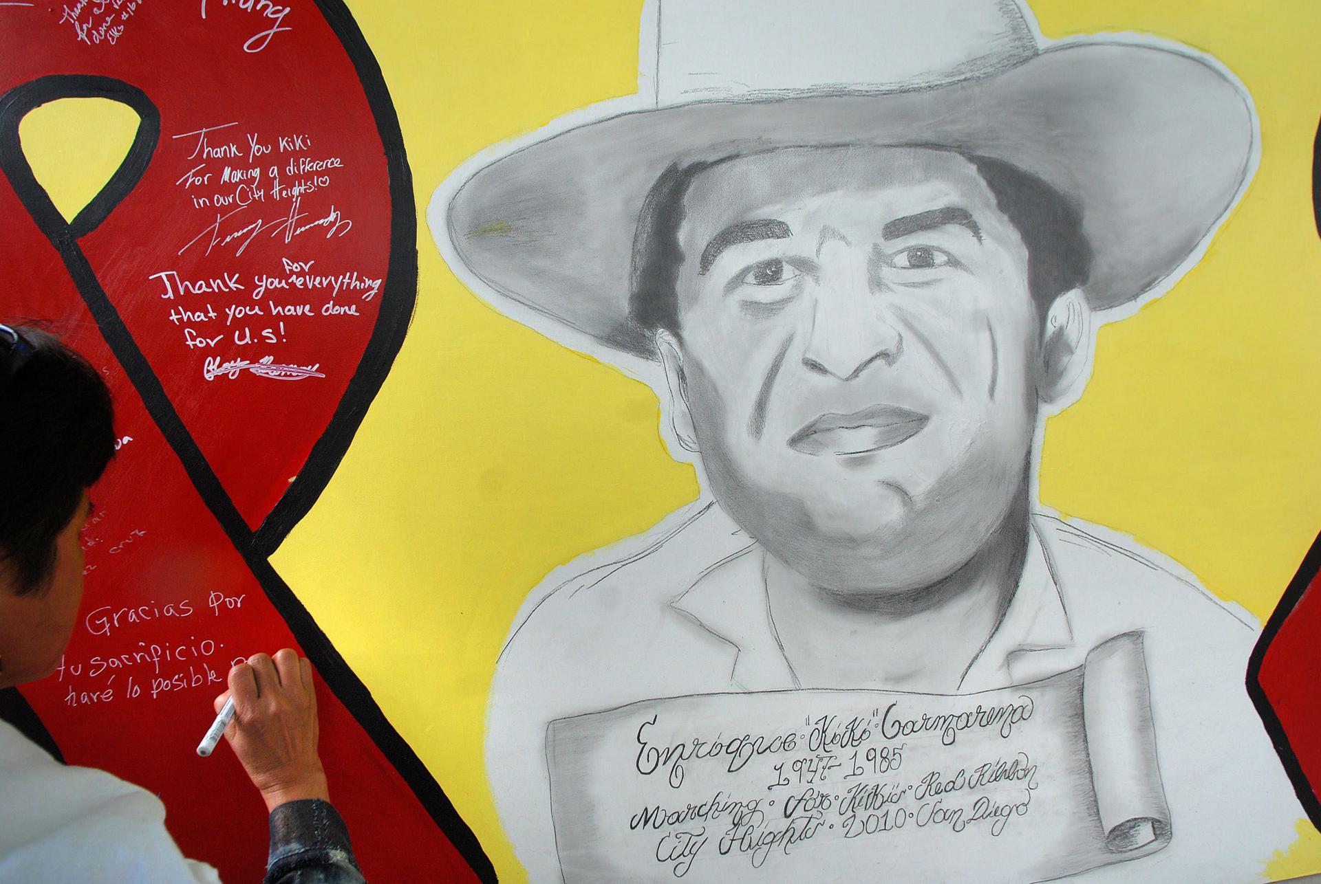 Fotografía de archivo de una mujer que escribe un mensaje sobre un mural con el rostro de Enrique "Kiki" Camarena. EFE/David Maung