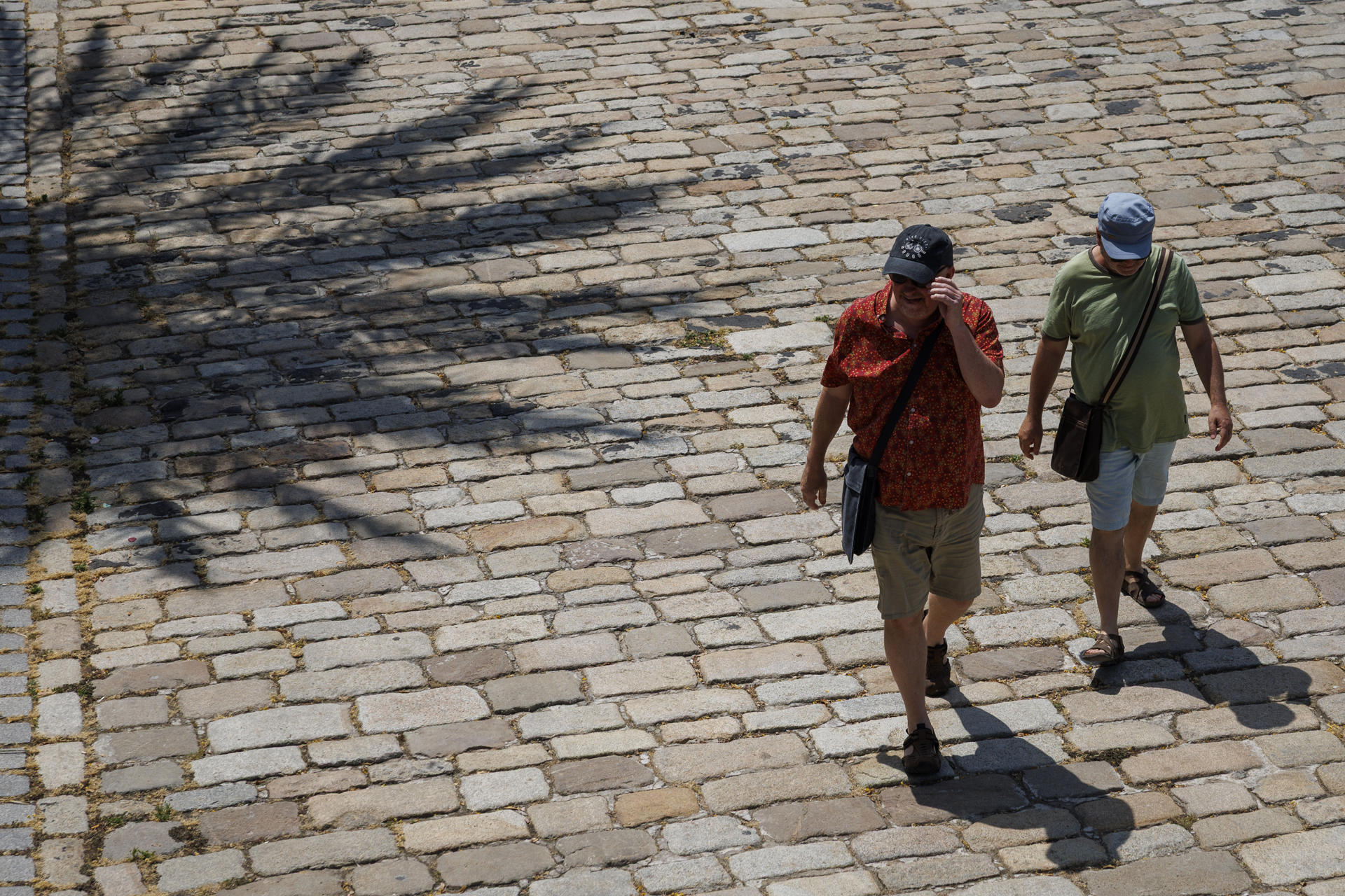 Unos turistas caminan por el paseo fluvial del Guadalquivir de Sevilla este sábado. EFE/ Julio Muñoz