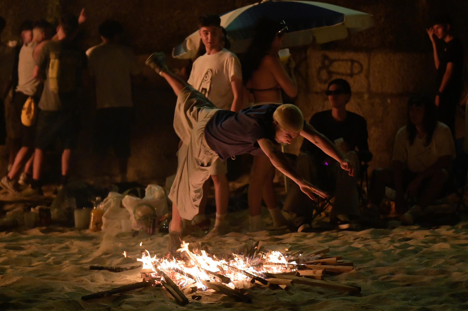 Un chico salta una de las hogueras encendidas en la playa coruñesa de Riazor durante la celebración de la noche de San Juan. EFE / Moncho Fuentes.
