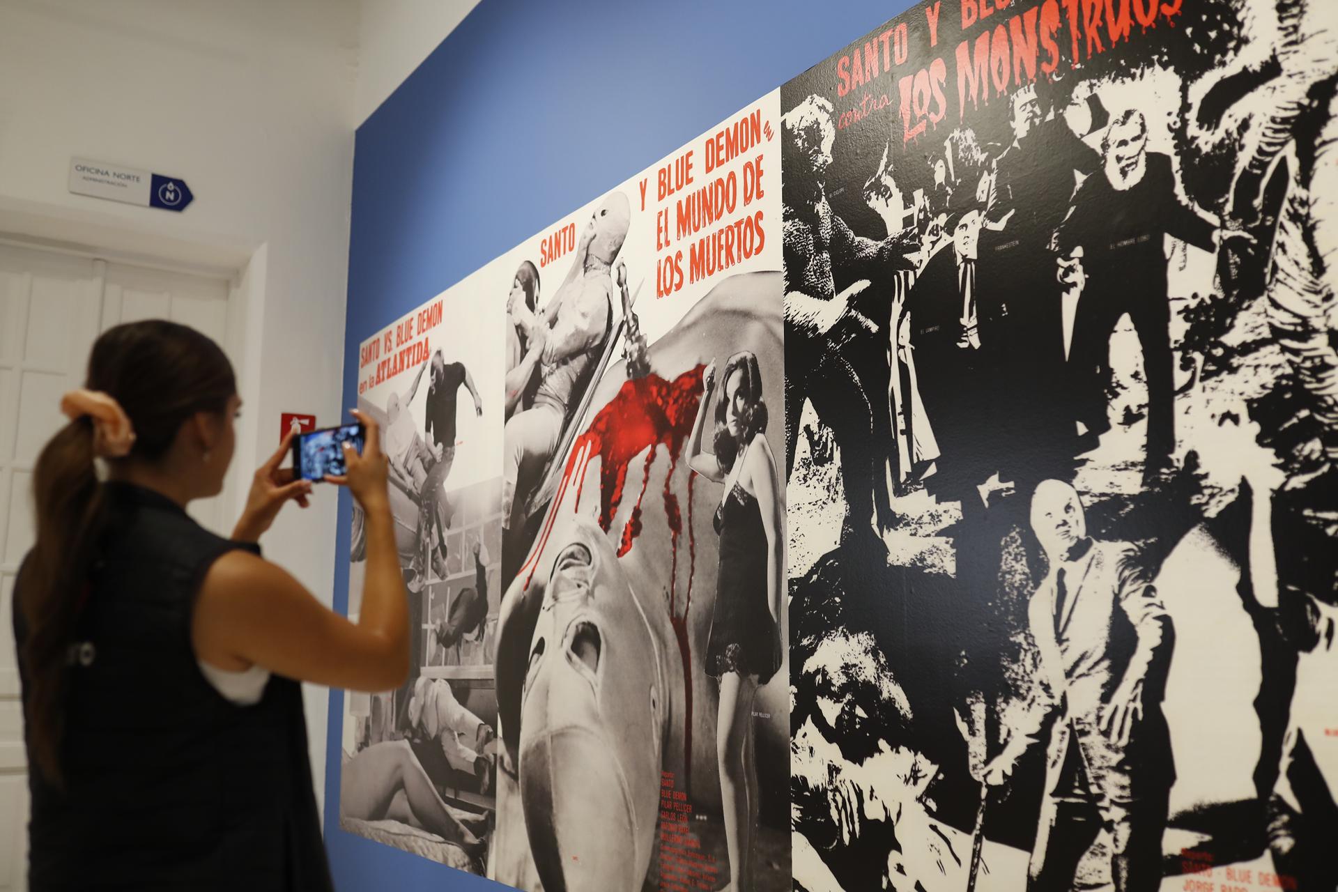 Una mujer toma una fotografía de la exhibición de lucha libre mexicana 'Kartharsis' este jueves, en el Museo de las Artes (MUSA) en Guadalajara (México). EFE/ Francisco Guasco
