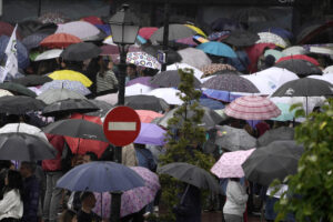 Decenas de personas se protegen de la lluvia este domingo en Oviedo. EFE/Paco Paredes